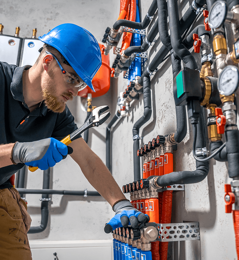 Plumber working on mechanical systems with pipes and gauges